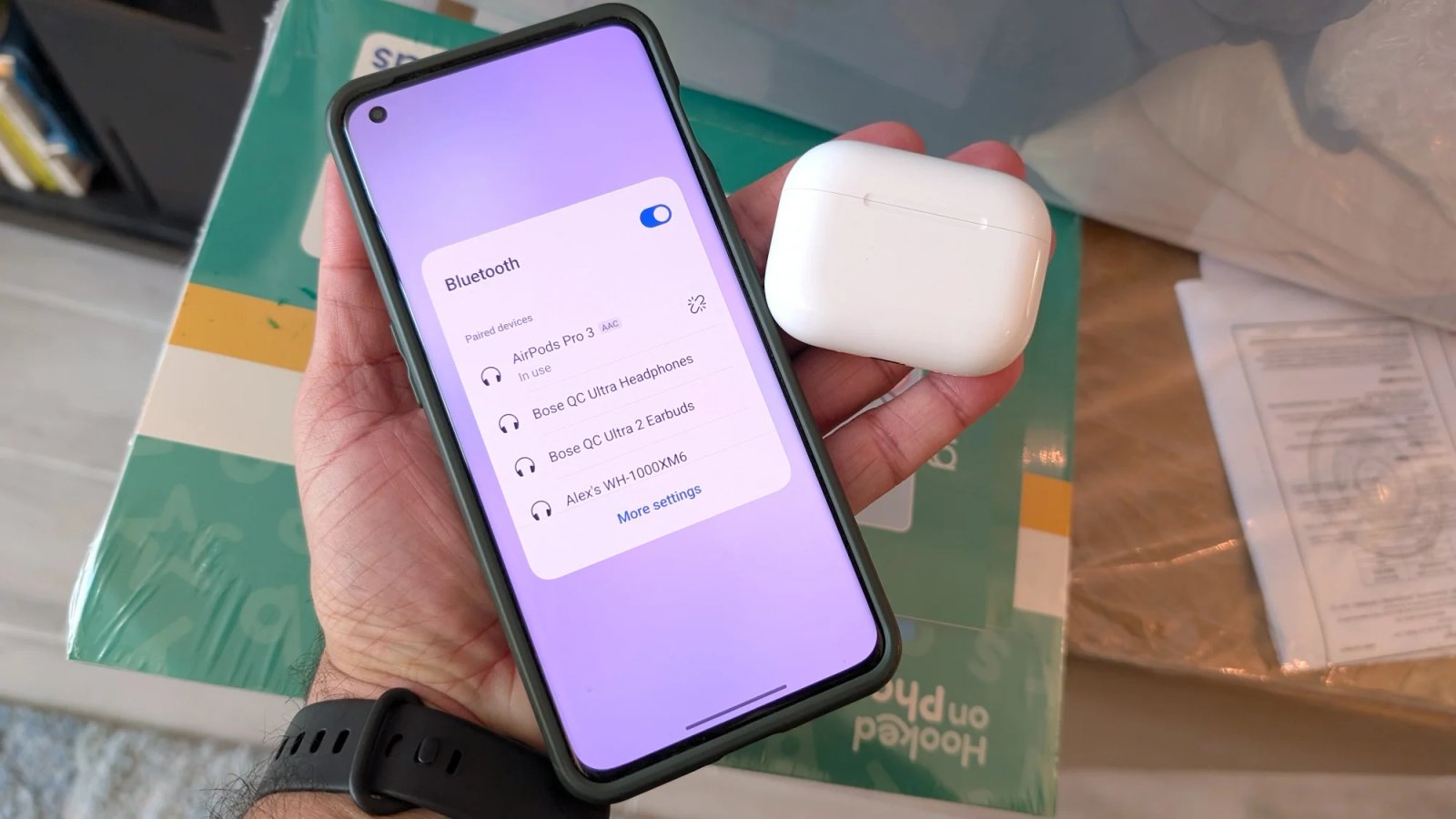 A Google phone with the screen showing that it is paired to the Apple AirPods Pro 3 next to them